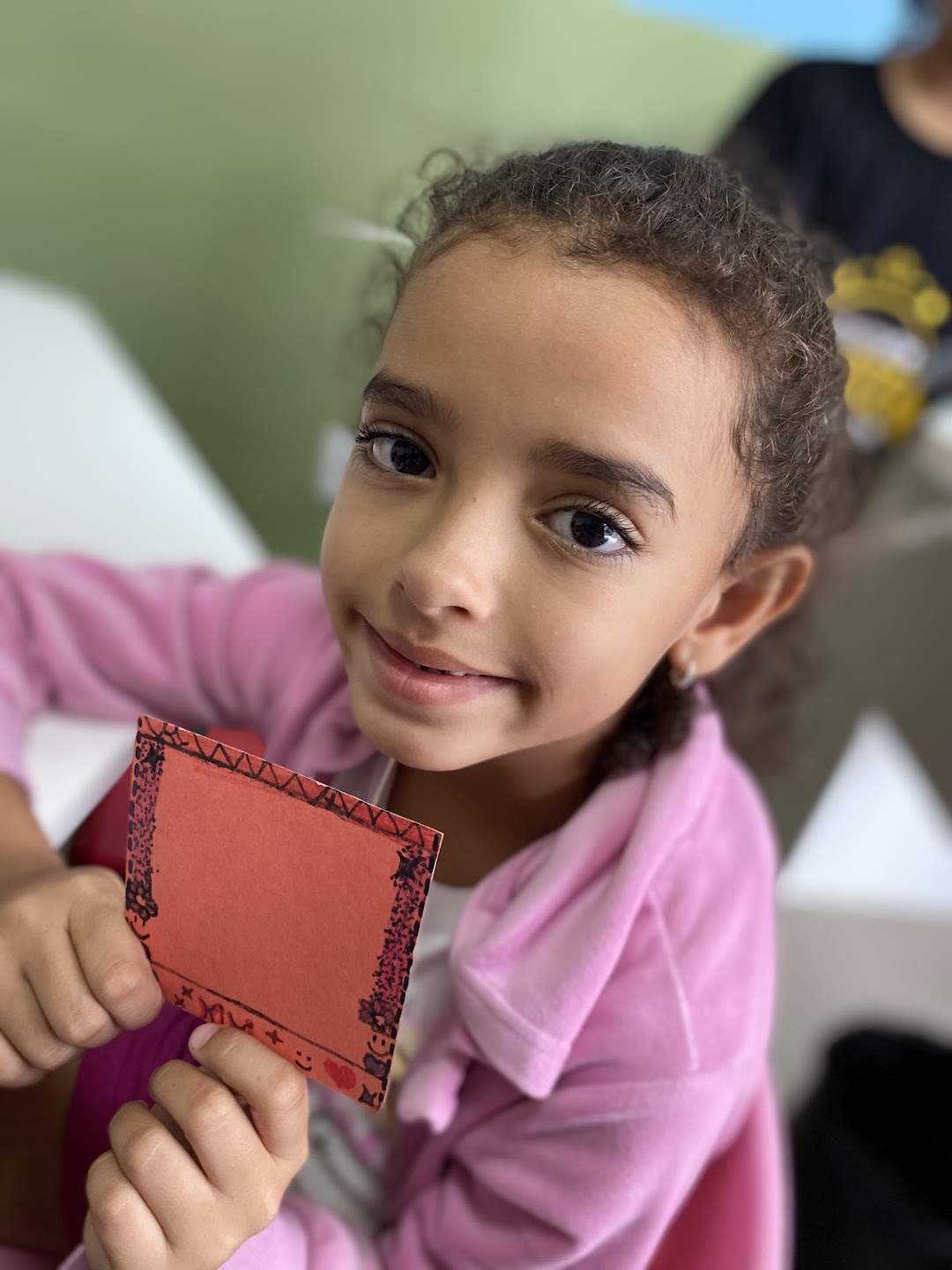 Criança mostrando trabalho manual em papel vermelho