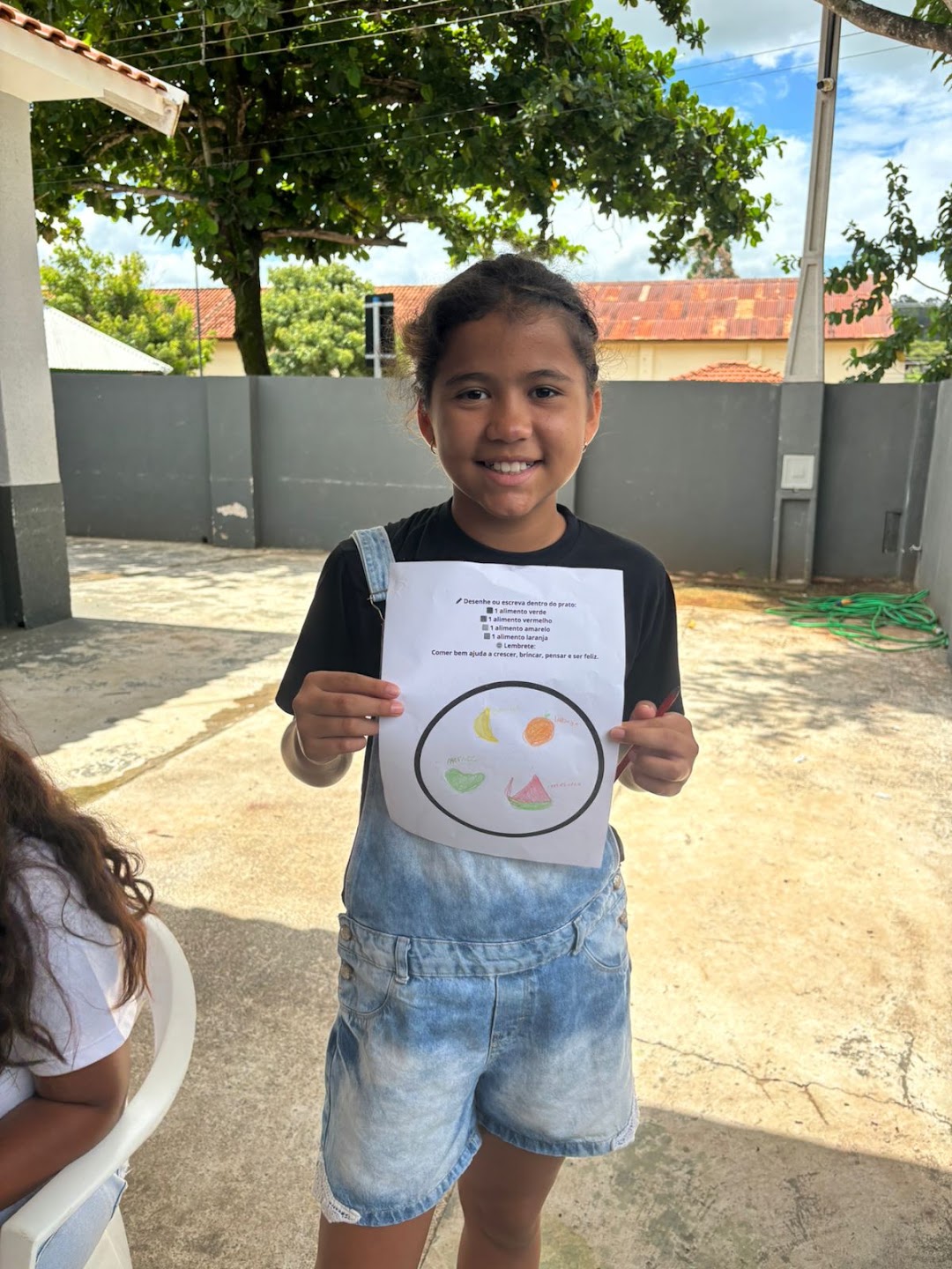 Criança do Instituto sorrindo e mostrando a atividade que realizou